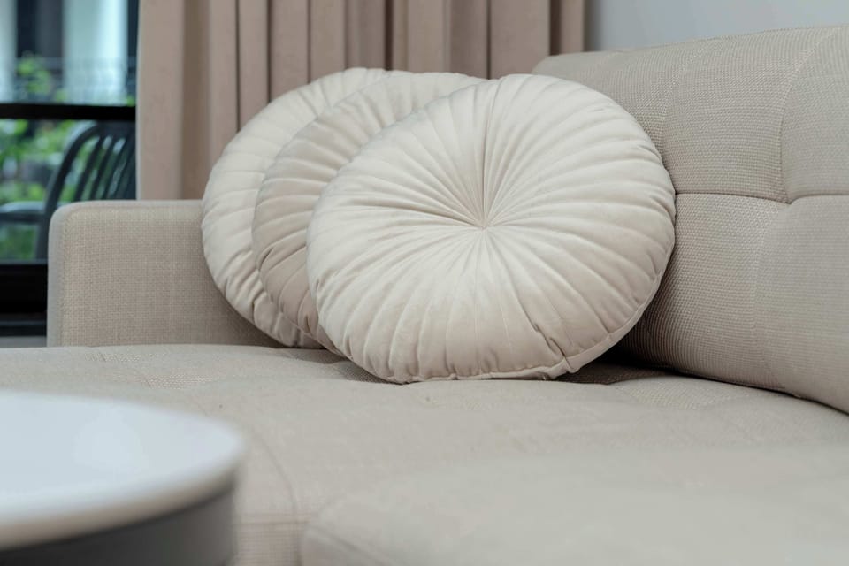 A close-up of a soft sofa with a round decorative cushion.