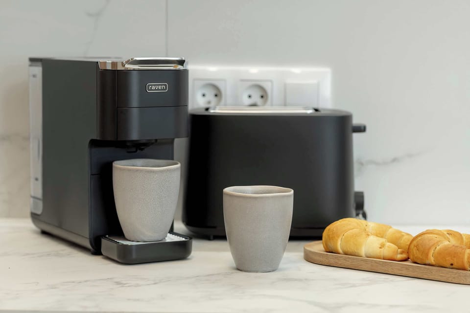 A coffee station with a coffee machine, cups, and a bowl of bread.