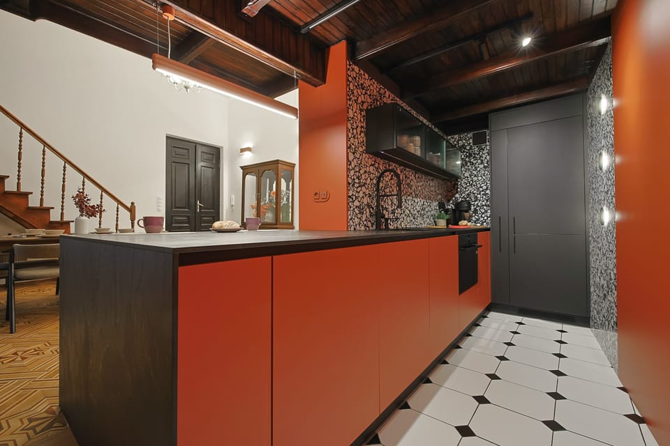 The terracotta kitchen island with a black countertop opens directly to the dining area and traditional wooden staircase.