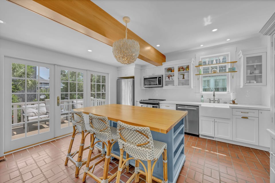 Gather at the sunny island with its warm butcher block top, perfect for morning coffee or meal prep. Beyond the french doors, your private patio awaits for outdoor dining under the palms.