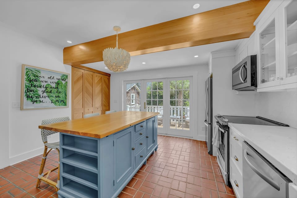 Step into a bright, welcoming kitchen where your culinary adventures await. The spacious island and abundant counter space make meal prep a breeze, while natural light pours in through elegant French doors.