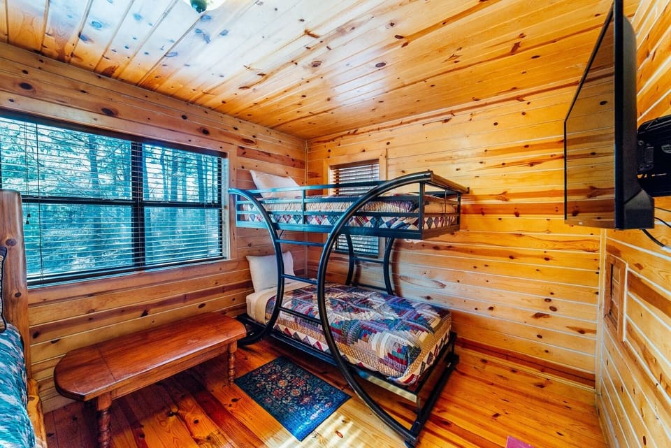 Rustic charm meets cozy comfort in this inviting bunk room, where warm knotty pine surrounds you and a peaceful forest view greets your morning. Perfect for families or friends seeking a mountain retreat.