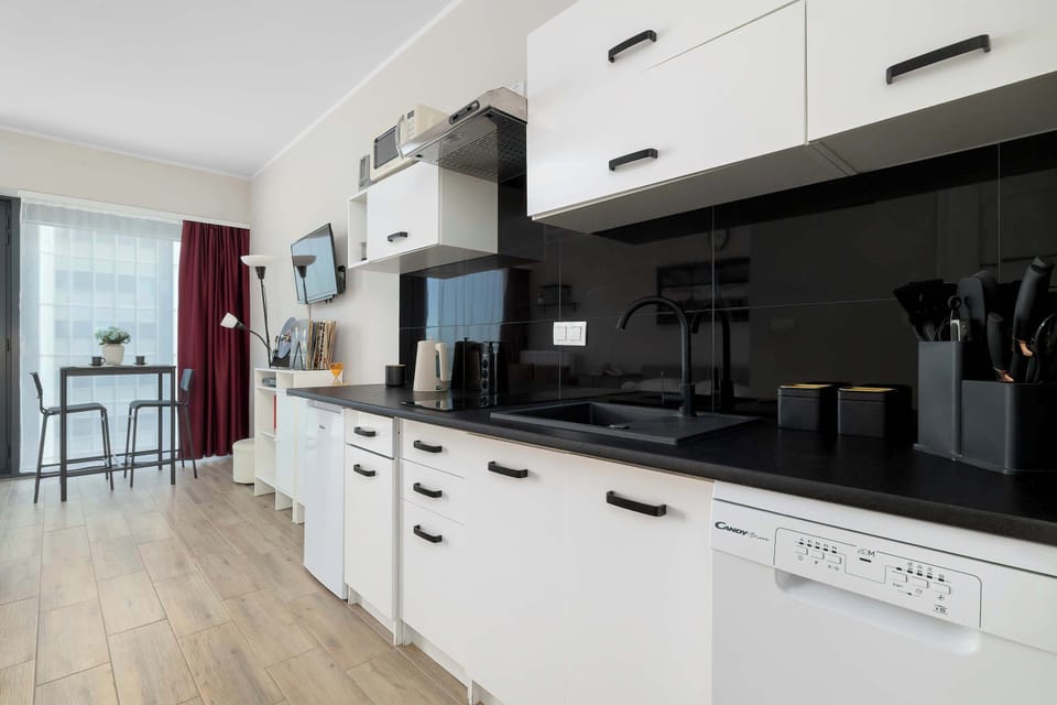 Kitchenette features white lower units, a dark countertop, and a small dining nook with a high table and chairs.