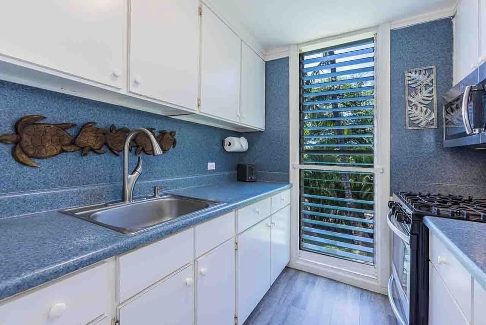 Your kitchen invites you to prepare meals with ease, featuring charming tropical garden glimpses through louvered doors.