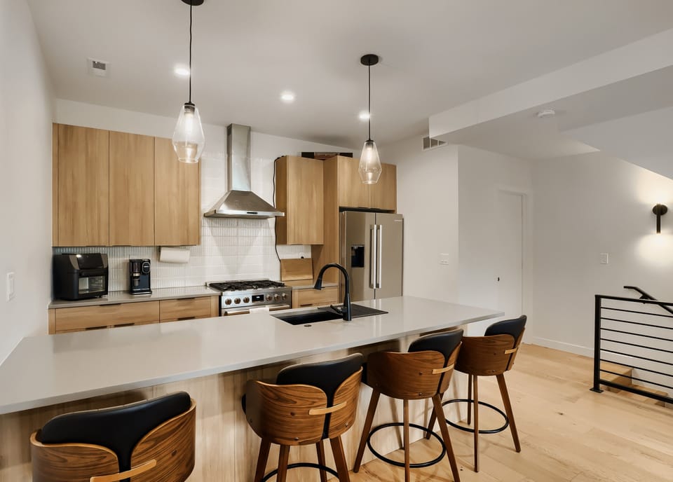 Gather around this sleek kitchen island for your morning coffee or casual meals. Modern appliances and warm wood cabinetry create a stylish space for cooking and connecting.