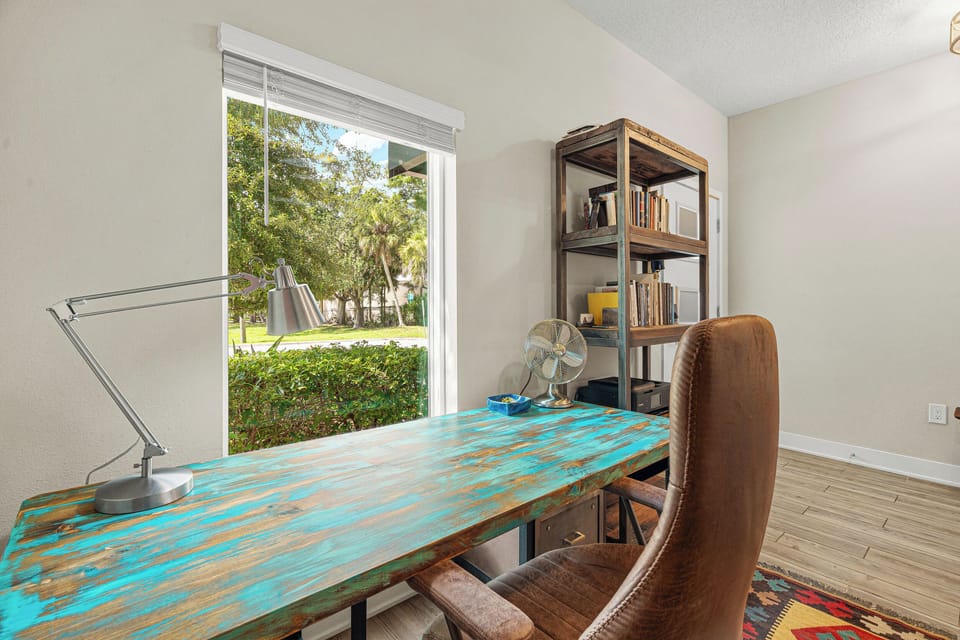 Your workspace overlooks the neighborhood's lush greenery through a large window, while a vintage desk and open shelving set a creative, inspiring tone for your stay.