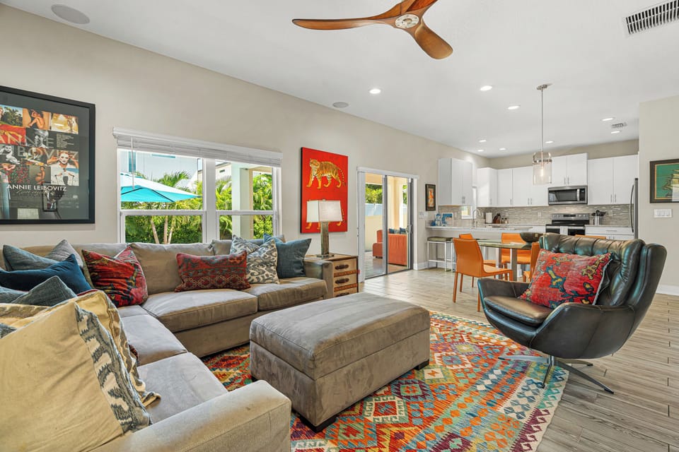 Picture yourself relaxing in this vibrant open-plan retreat, where mid-century style meets tropical ease. Sink into plush seating as the ceiling fan keeps you cool, then step through French doors to your private outdoor oasis.