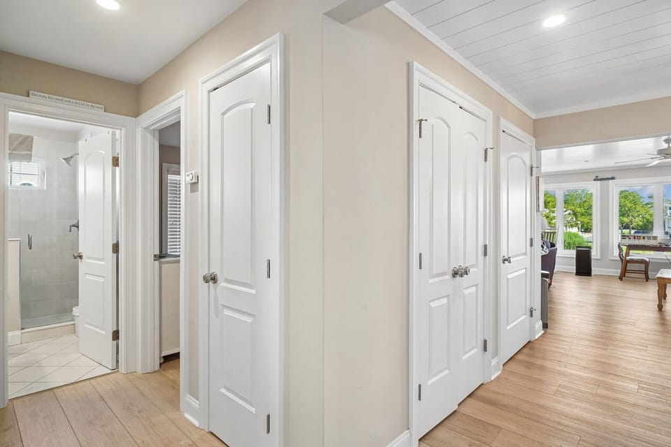 Your private hallway features gleaming hardwood floors and soaring vaulted ceilings, with doors leading to both bedroom and bathroom spaces—creating a bright, airy flow throughout your retreat.