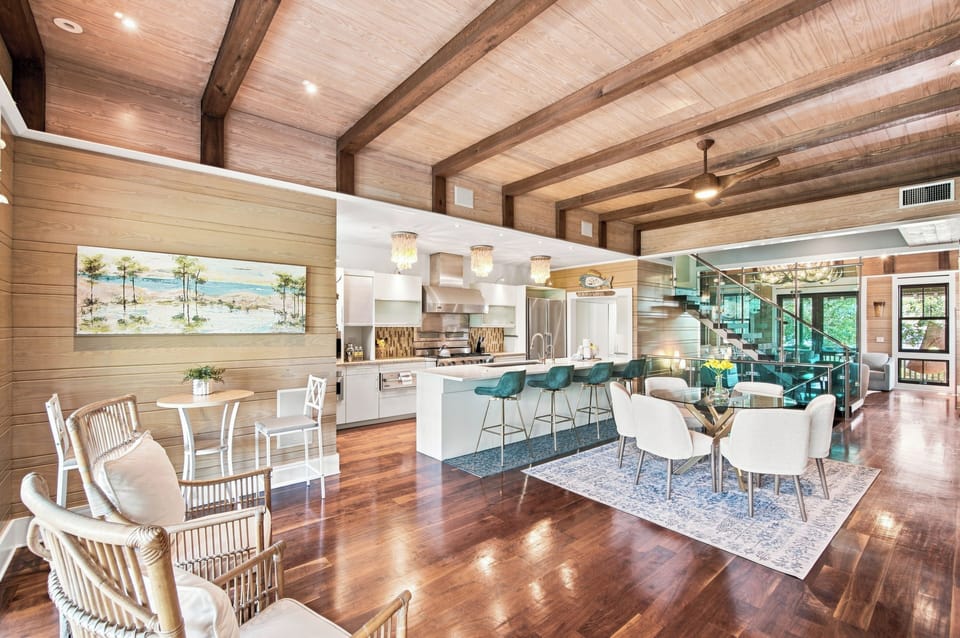 Step into your open-concept coastal retreat, where soaring wood-beamed ceilings and warm hardwood floors invite you to relax. The bright kitchen and spacious dining areas flow effortlessly, perfect for gathering and creating memories.