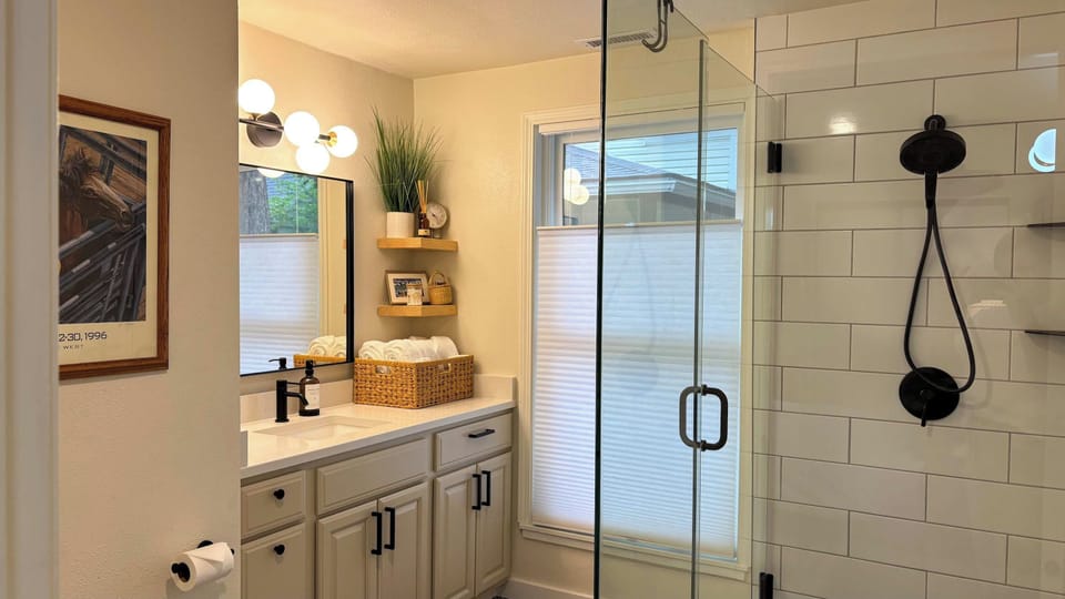 Bathroom (Glass Shower): Modern bathroom with shower, black fixtures, and
Western‐themed artwork.