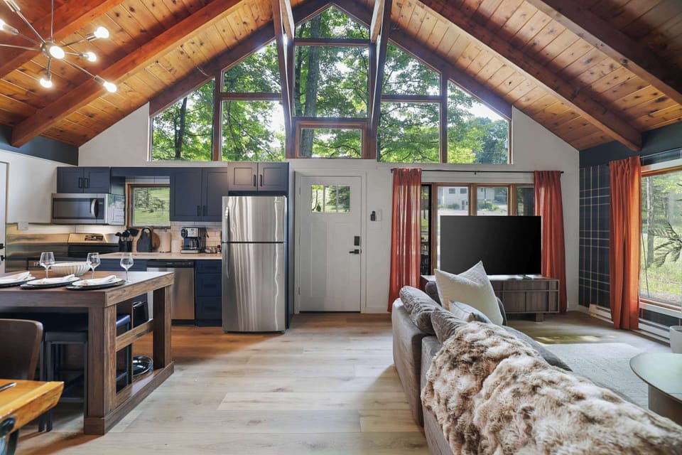 Towering windows fill this open-concept space with light, blending the kitchen and living room into one bright, welcoming hub for the whole group.