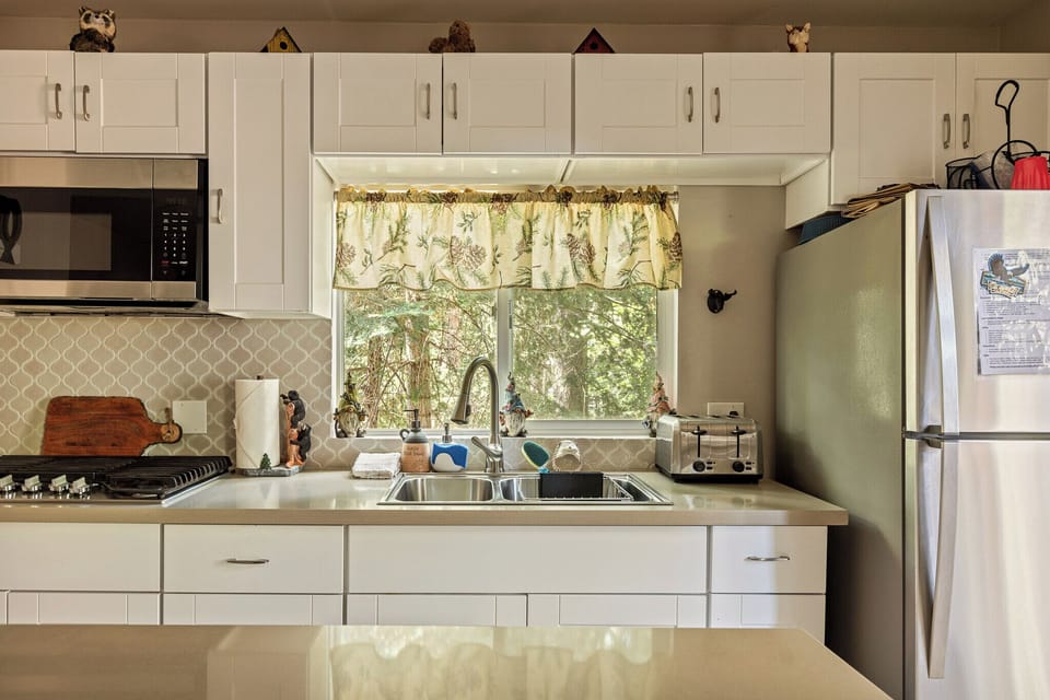 Bright white kitchen with forest-view window and stainless appliances