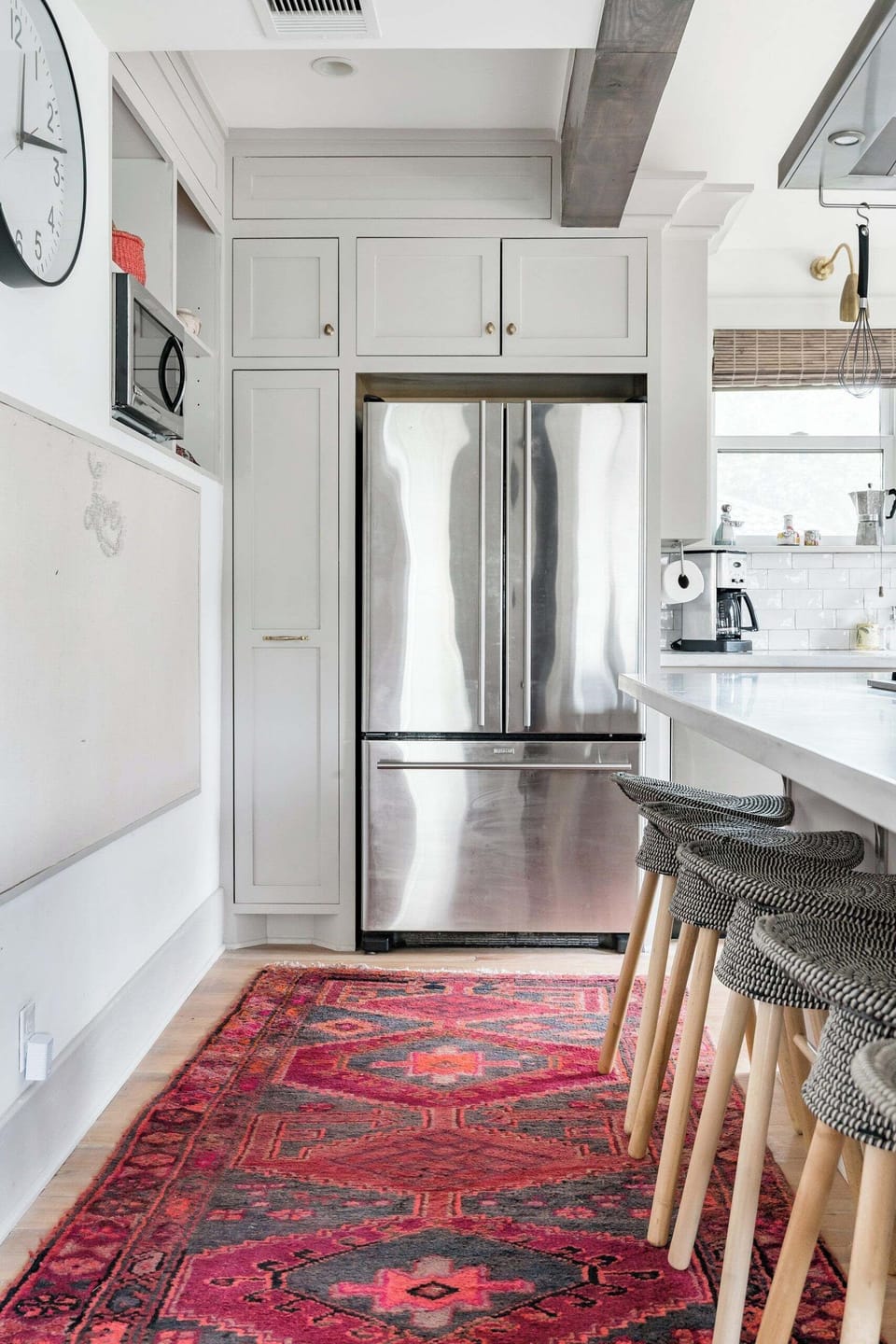 Bright designer kitchen with breakfast bar, custom cabinetry, and bold runner rug