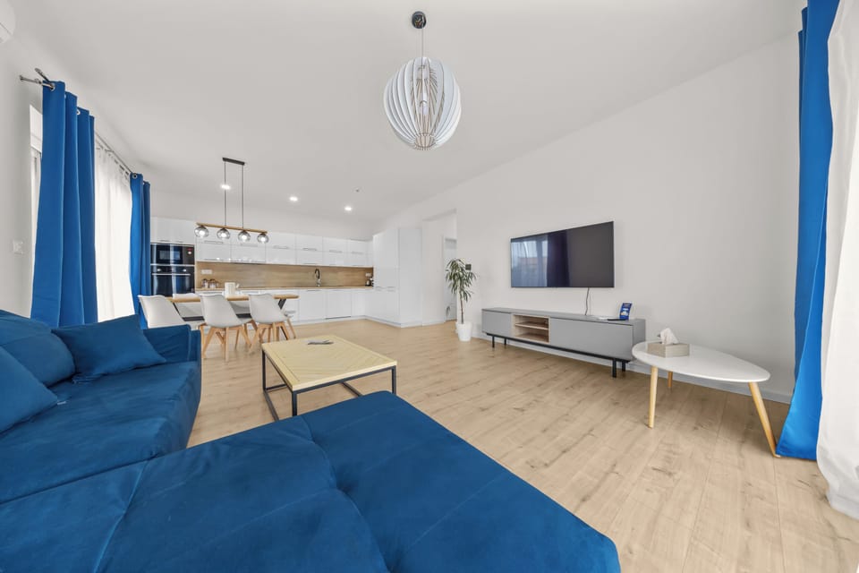 Bright open-plan lounge with modern kitchen, dining area & large TV