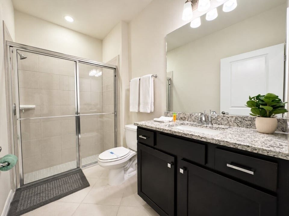 Modern full bathroom with spacious vanity and glass-enclosed shower.