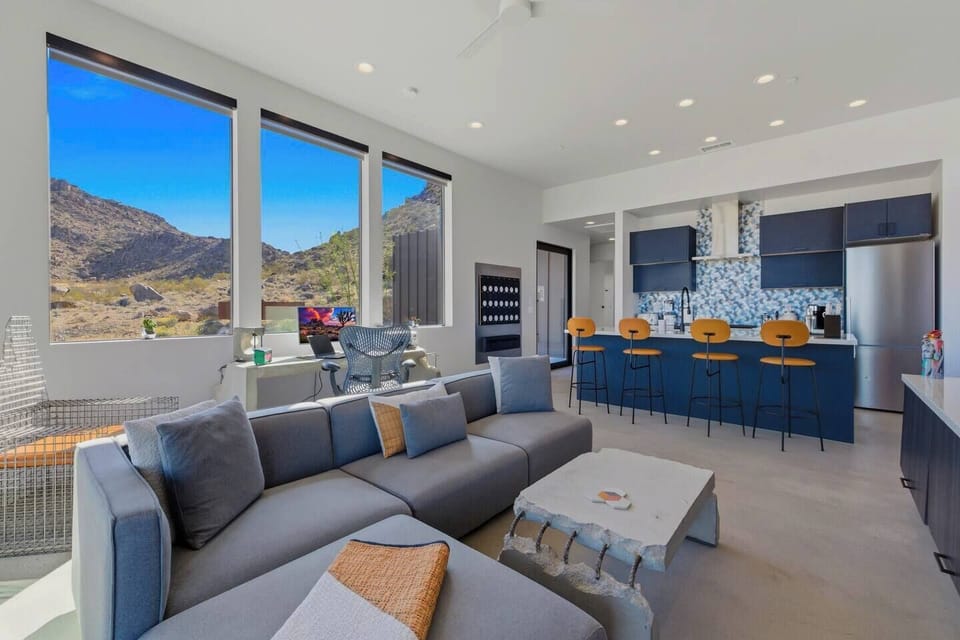 Sunny open-plan living room and chic kitchen with bar, stunning mountain views