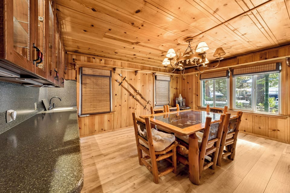 Dedicated dining room featuring a rustic wood dining table with seating for group meals, highlighted by a pinecone-themed chandelier.