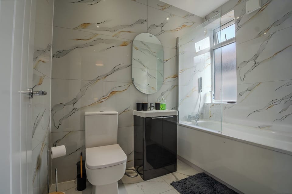 Elegant Bathroom: Sleek marble-effect tiled walls with gold veining, modern black vanity, and a luxurious walk-in shower
