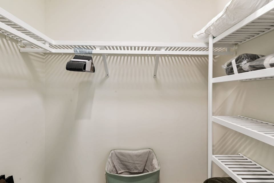 A spacious walk-in closet with organized shelving awaits your wardrobe, complete with a hair dryer and ample storage to keep your vacation essentials neatly arranged.