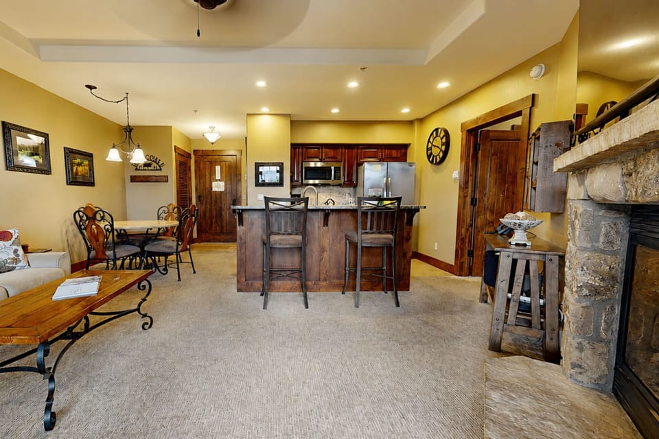 Open-concept living space with a fully equipped kitchen, stone fireplace, and cozy seating areas. Your perfect mountain retreat for unwinding and connecting.