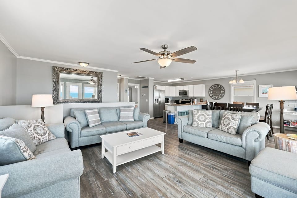 Gather together in this bright, open-concept living room featuring soft plush seating and cool coastal finishes.