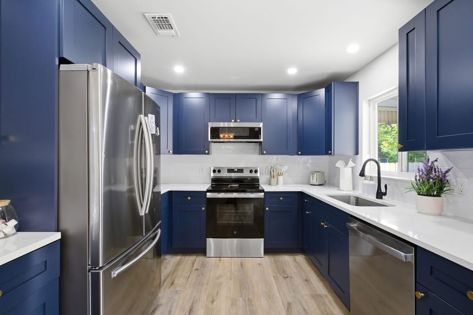 Fully Equipped Kitchen with Navy Cabinets, Stainless Appliances, Samsung Refrigerator, GE Electric Stove, and Dishwasher. Cookware, Dishes, and Cooking Basics provided.
