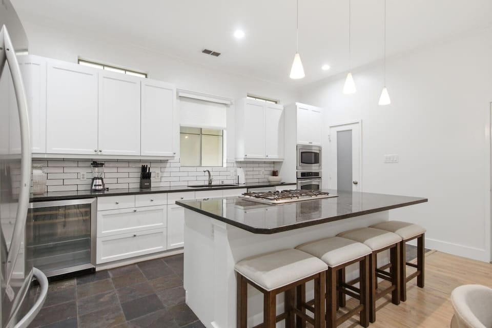 Open kitchen with pendant lighting, dark granite countertops, and island bar seating. A well-designed layout that makes cooking for a group easy, comfortable, and actually enjoyable.
