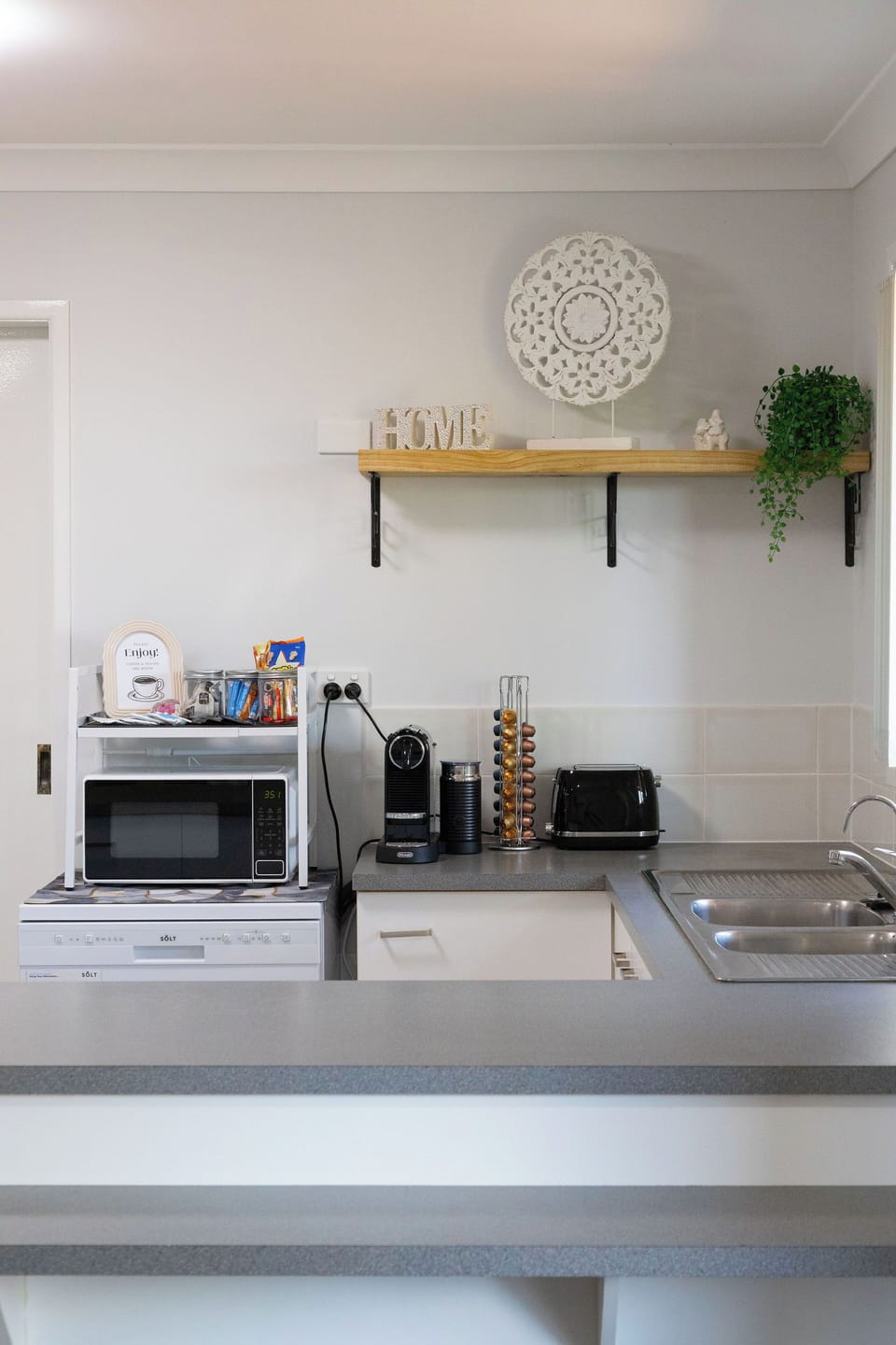 Bright kitchenette with coffee bar, microwave, toaster and sink.