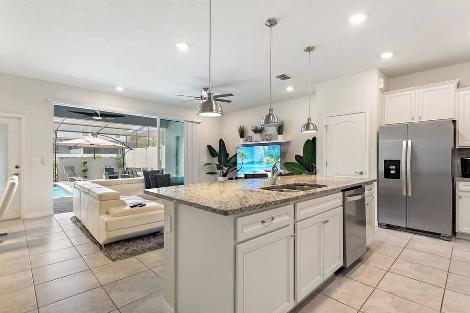 Spacious full kitchen with large island overlooking the living area and patio doors that open to the private pool—perfect for cooking, entertaining, and enjoying open, sun-filled views.
