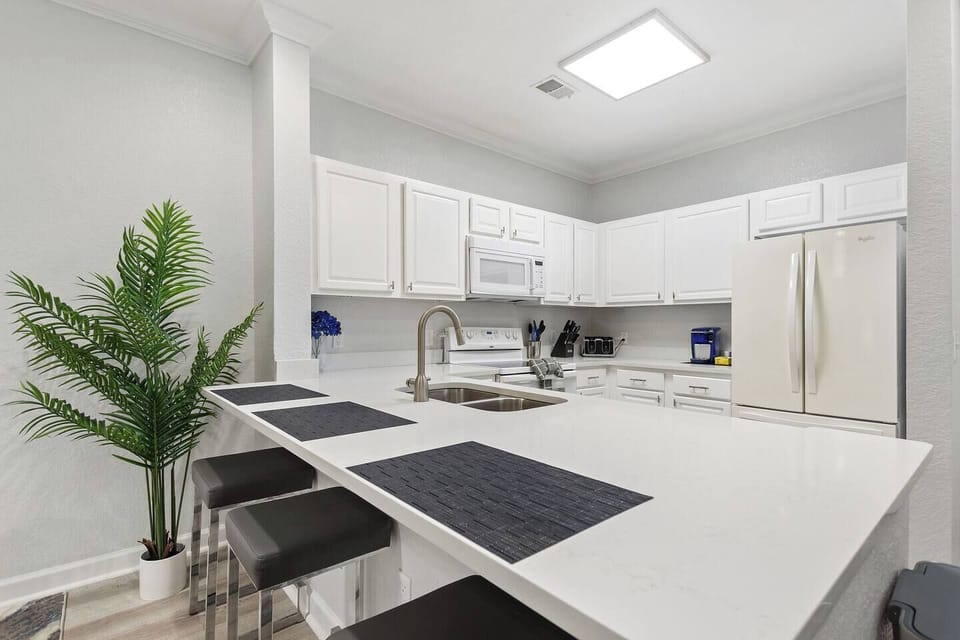 Gather around the bright, open kitchen island—perfect for casual meals or conversation while cooking. Features three comfortable bar stools and a seamless flow into the dining and living areas.