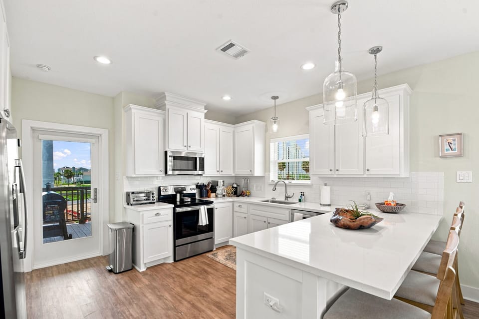 Bright modern kitchen with quartz island seating and patio water views