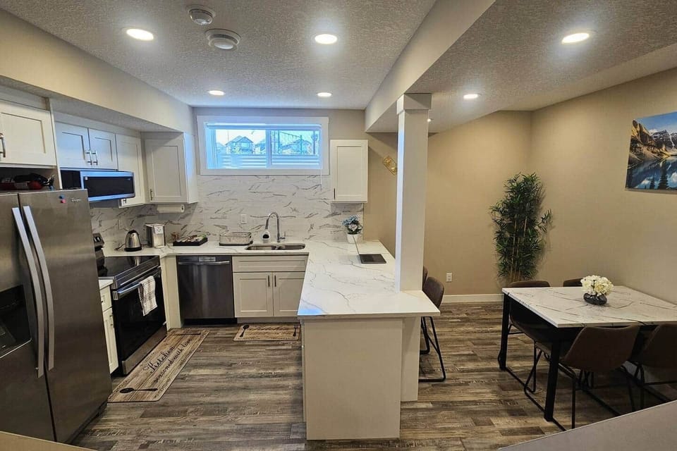 A fully equipped chef's kitchen features a dining table, bar stools, coffee machine with a variety of coffee options, electric kettle,  stove, dishwasher, and a freezer with an ice maker and water dispenser and much more to make you feel at home.