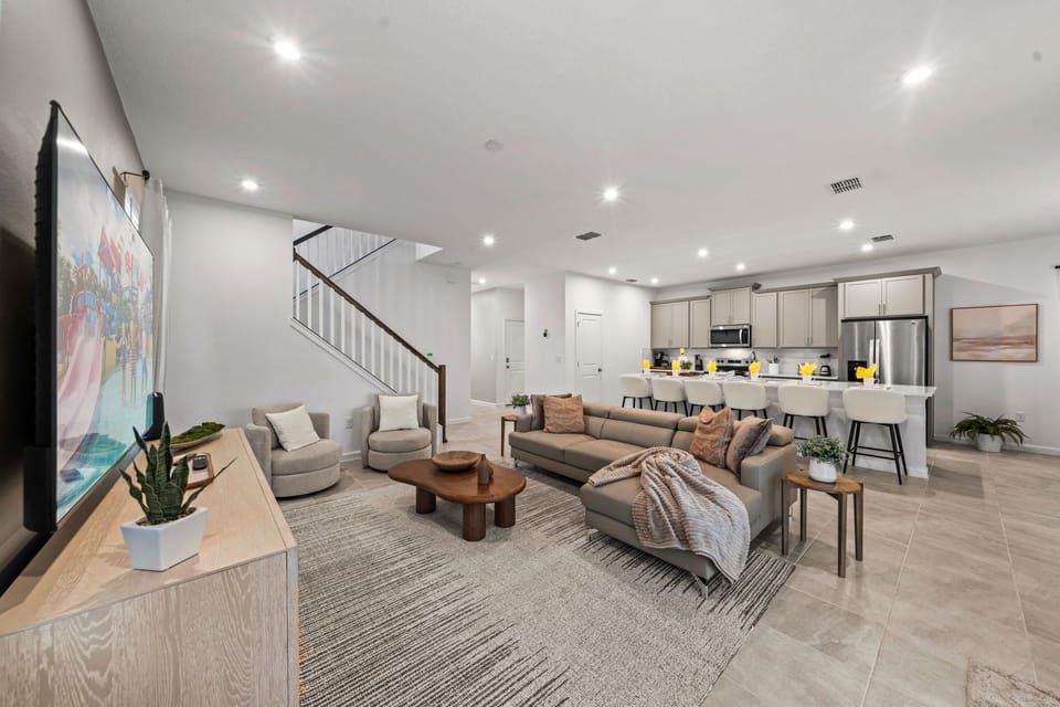 Gather in this bright open-concept living space with a comfy sectional, modern neutral decor, and a spacious kitchen just steps away-perfect for relaxing together.