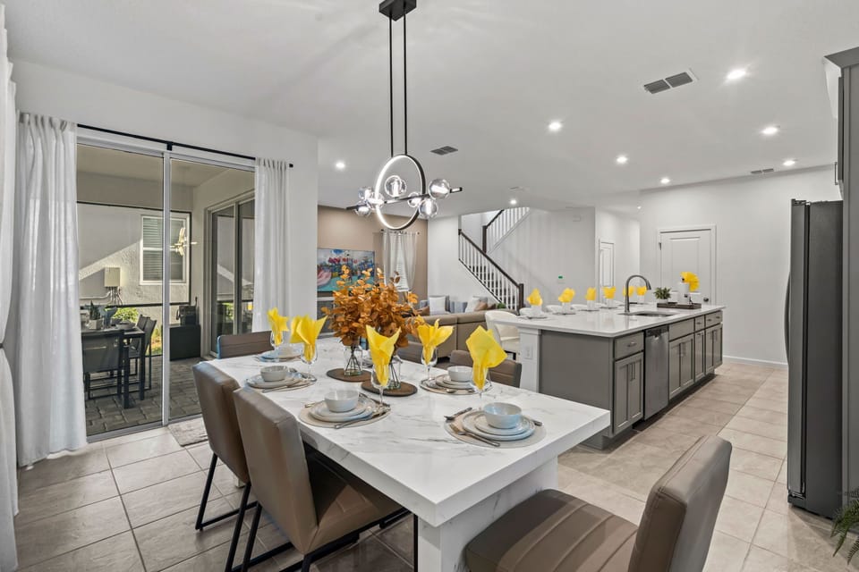 This stylish dining area flows into the modern kitchen, with a marble island, chic pendant lighting, and plenty of seating for group meals and easy entertaining.