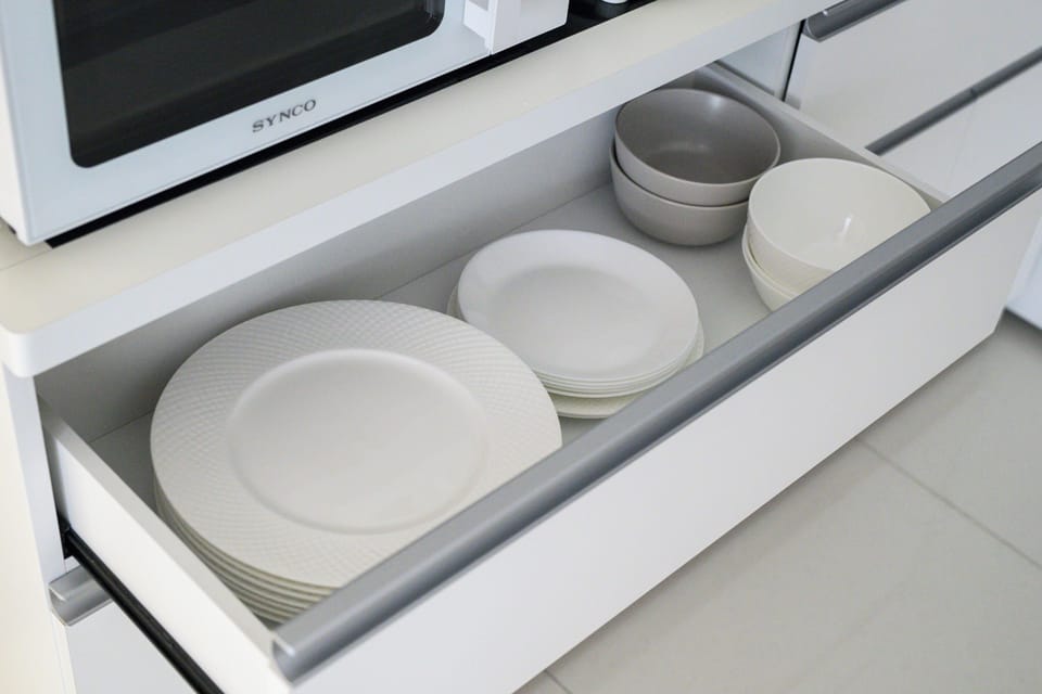 Well-stocked modern kitchen cabinet with glassware, mugs, and dining essentials