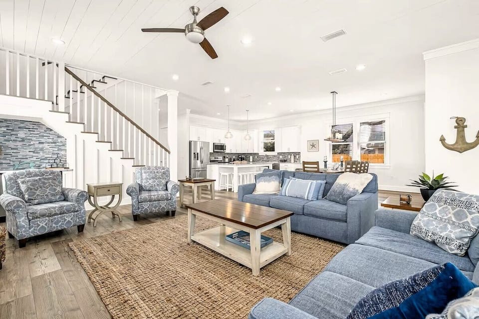 Main Living: Bright, open-concept main floor living space with warm hardwood flooring, plush sofas, and a wall-mounted 4K Smart TV—perfect for large group movie nights and family gatherings.