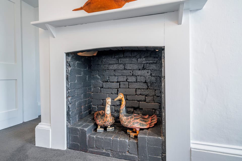 The decorative fireplace celebrates the apartment's heritage character, accented with quirky décor that makes every corner feel thoughtfully curated.