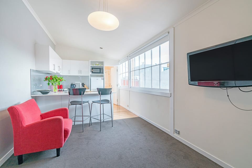 Beside the kitchen, comfortable armchairs and a wall-mounted TV create a peaceful corner for reading or your favourite show.