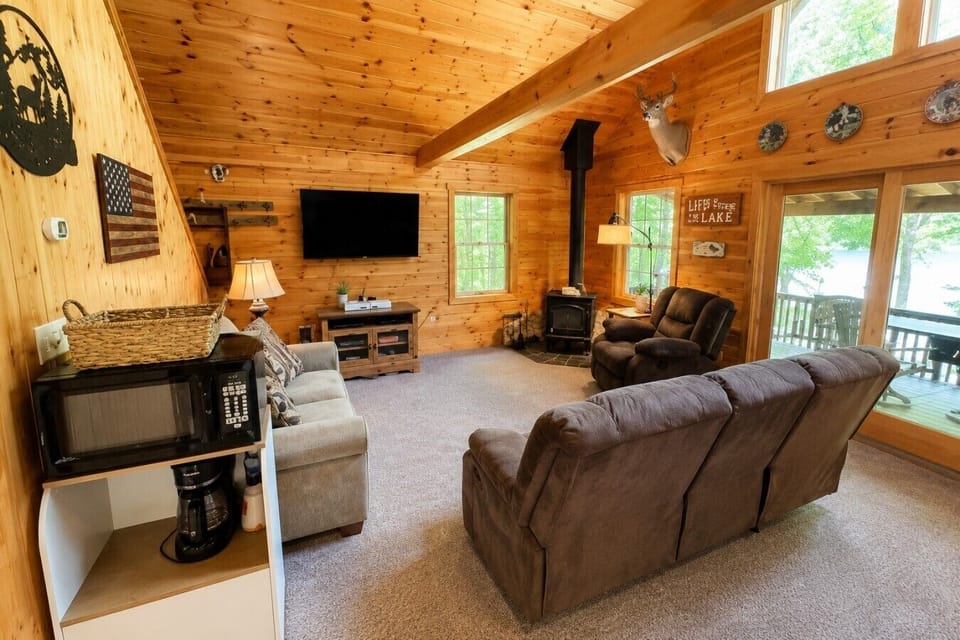 Cozy cabin living room with comfortable seating, a wood stove, and beautiful lake views.