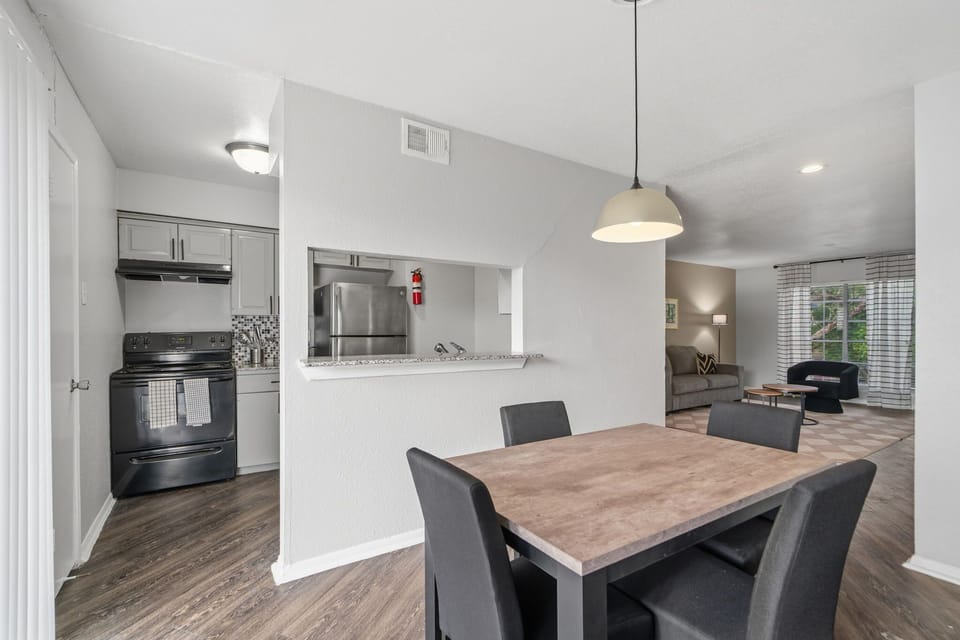 Open-plan dining area with a wood dining table, upholstered seating, and a convenient pass-through to the fully equipped kitchen.
