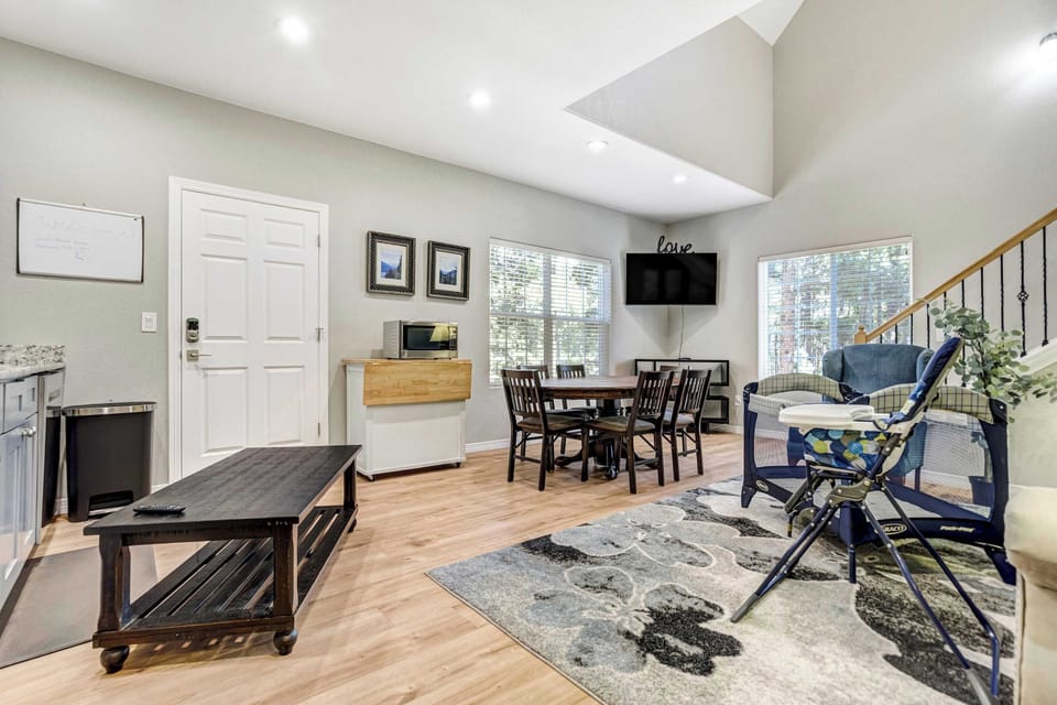 Vaulted ceilings and a skylight pour daylight across the open living and dining area. Light wood flooring, a wall mounted Smart TV, and a full dining table make this level feel bright, airy, and effortless to settle into.