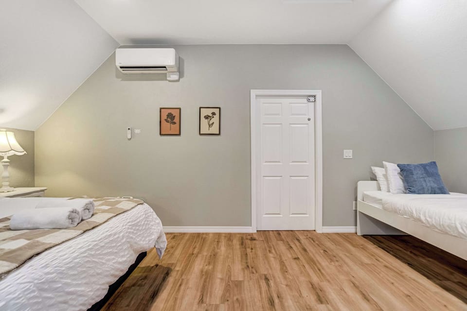 Framed art and warm neutrals soften the angled walls while the twin bed tucks in beneath the low side of the ceiling. Clear floor space runs right through the middle, useful for spreading out gear after a day on the trails.