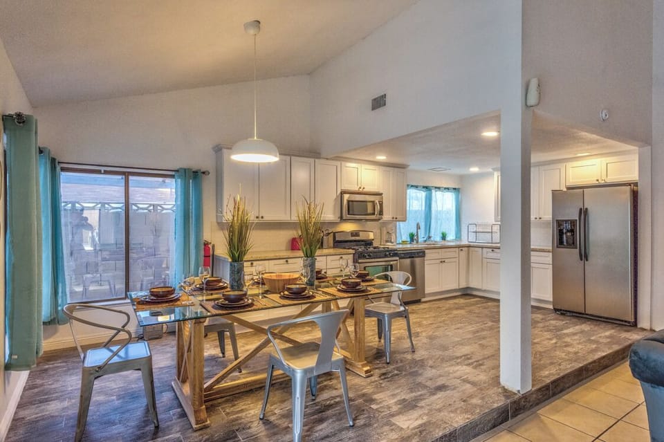 Bright open kitchen and dining area with patio access and vaulted ceilings