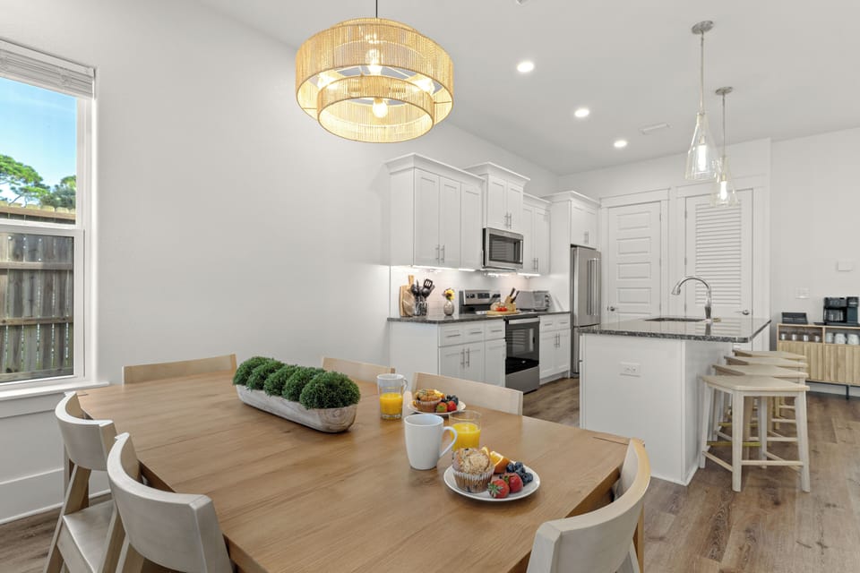 The dining area flows seamlessly into the modern kitchen, with a spacious table and island seating for easy group meals.