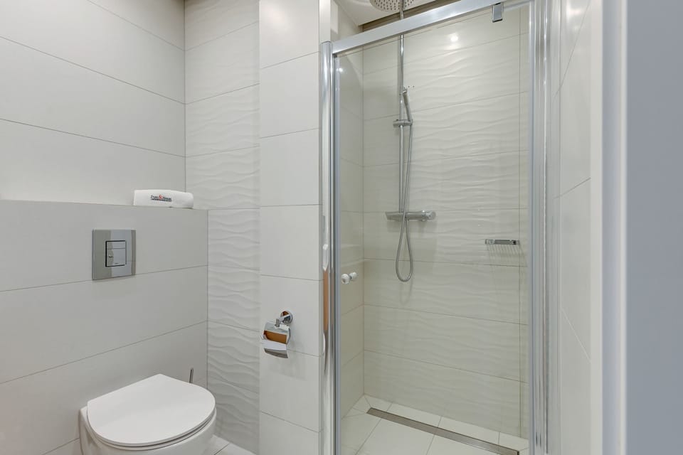 Bathroom with a modern shower, a large mirror, and a floating vanity. The light marble tones of the walls and floor create a clean and elegant look.
