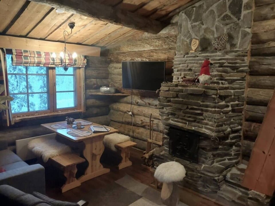 Living room with a stone fireplace, a television and a dining table with benches.