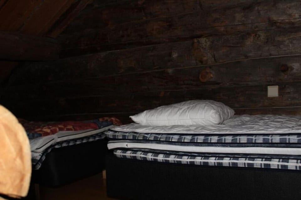Made-up bed in the loft beneath the exposed log wall.