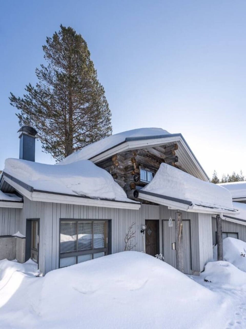 Exterior view of the log building under a thick blanket of winter snow.