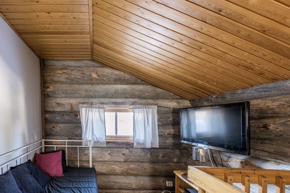 Loft lounge area with a flat-screen TV and extra seating under the sloped wooden ceiling.