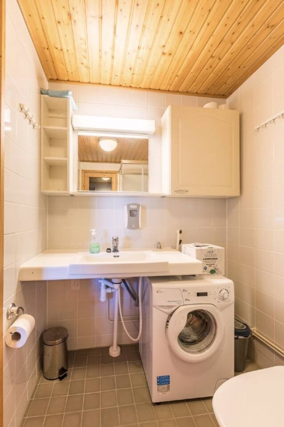 Washroom with a washbasin, mirror cabinet and a washing machine.